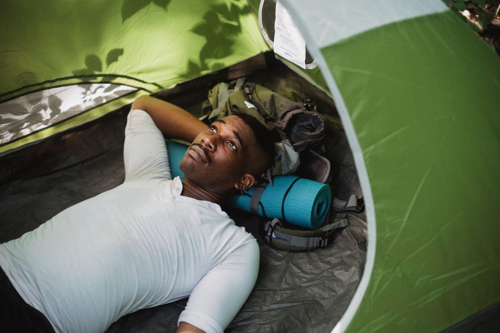 A man resting his head on a roll mat inside a tent