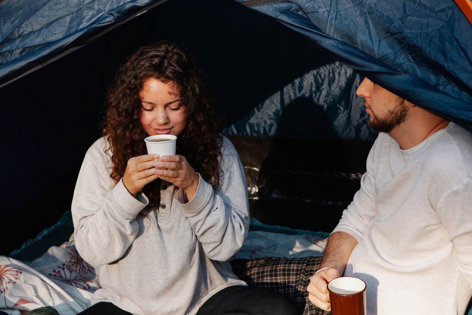 A couple drinking hot beverages inside a tent