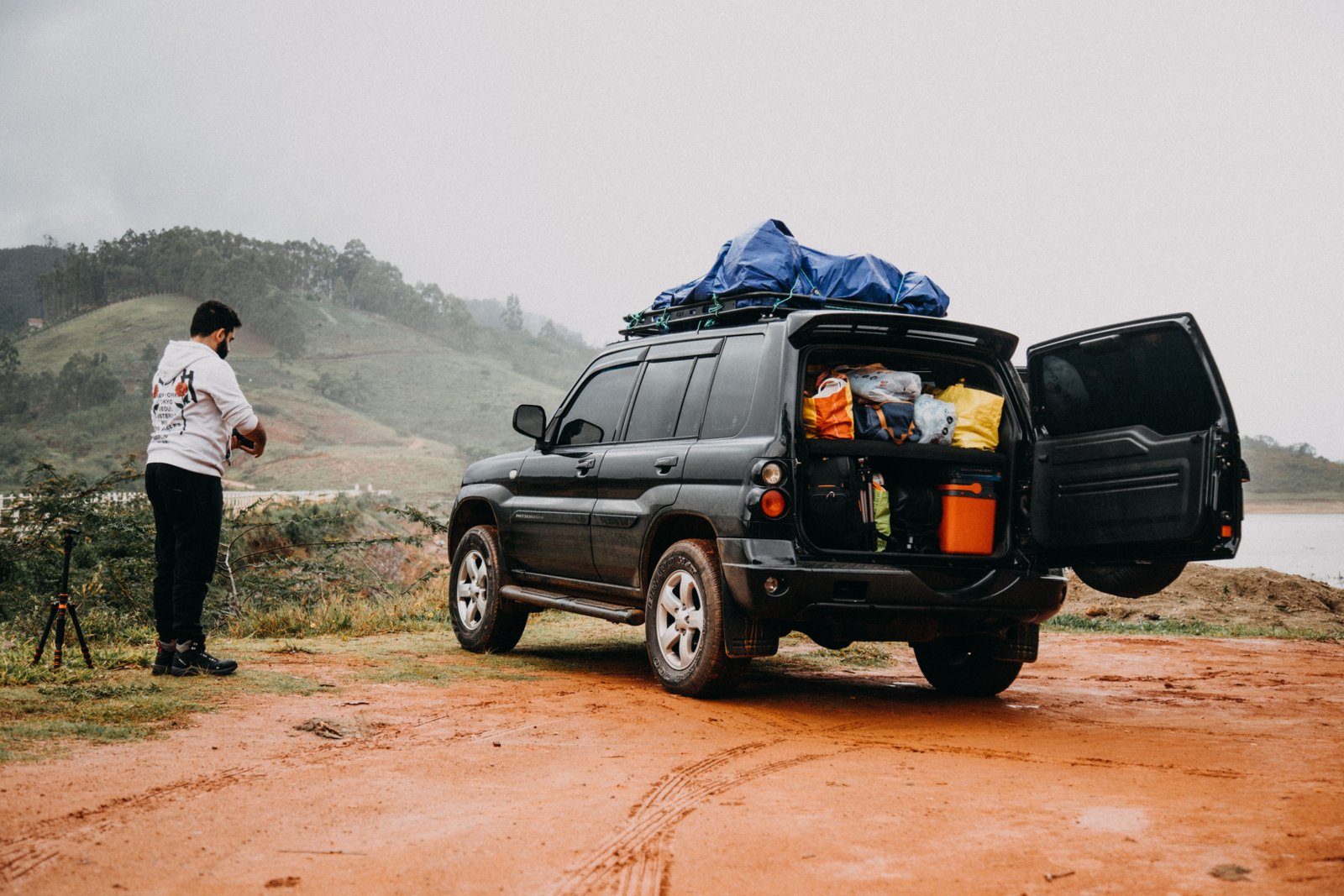 A man standing next to a car full of camping gear
